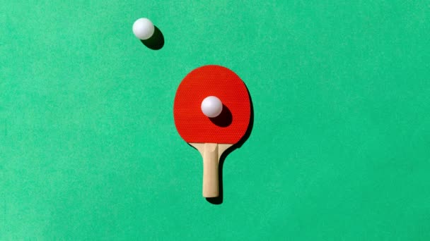 緑のテーブルの上に赤いピンポンテニスラケットとパターンとして白いボールの動き スポーツ エンターテイメント レクリエーションの最小限の概念 高品質のフルHd映像 — ストック動画
