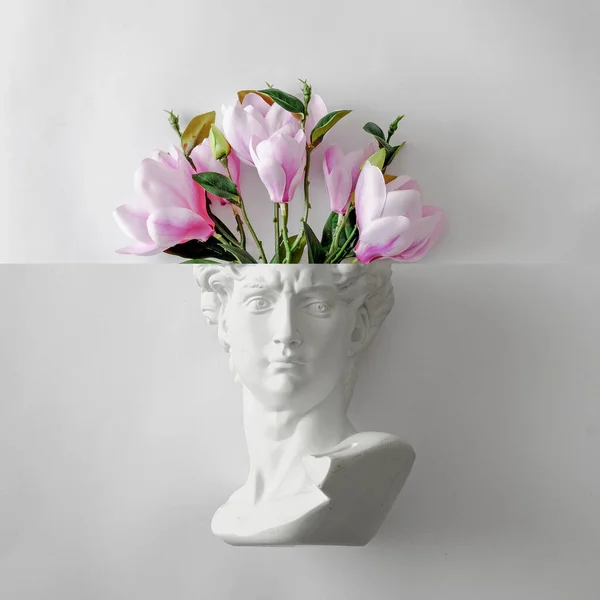 Davids statue bust of Michelangelo and a bouquet of flowers like a brain. Minimal playful concept of spring gift and creativity and art. High quality photo