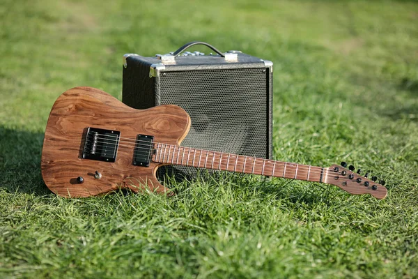 Electric guitar and amplifier outdoors on the green fresh grass
