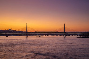 Körfez boyunca uzanan Golden Horn metro köprüsü gün batımında aydınlandı, İstanbul, Türkiye
