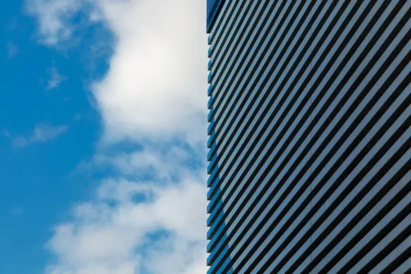 外観に反復パターンを持つ近代的な建物の一部の最小限の写真は 部分的に曇った空に対して際立っています ストック画像