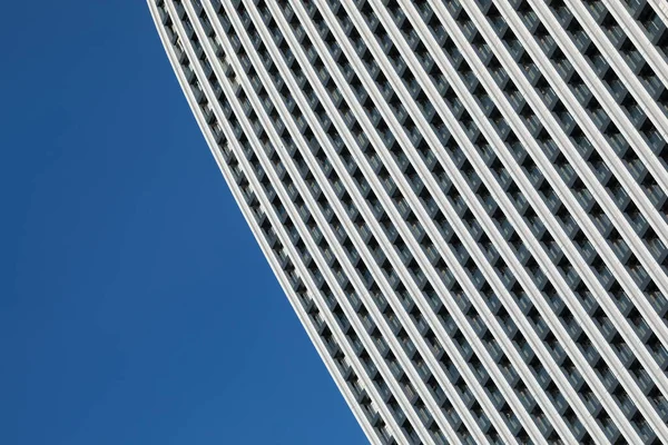在明亮的蓝天下 一幅简约的照片映衬着一座外型重复的现代建筑的一部分 免版税图库照片