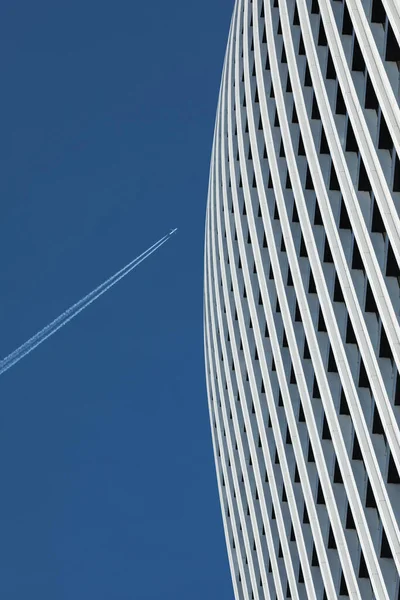 摩天大楼的细部与有飞机痕迹的蓝天相映成趣 图库照片