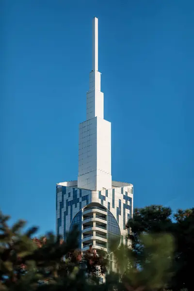 有尖塔的现代建筑耸立在绿树成荫的蓝天之上 免版税图库图片