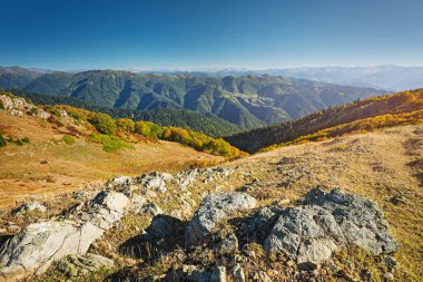 Yuvarlanan tepeler ve kayalık arazi uçsuz bucaksız yeşil bir vadiye tepeden bakar.