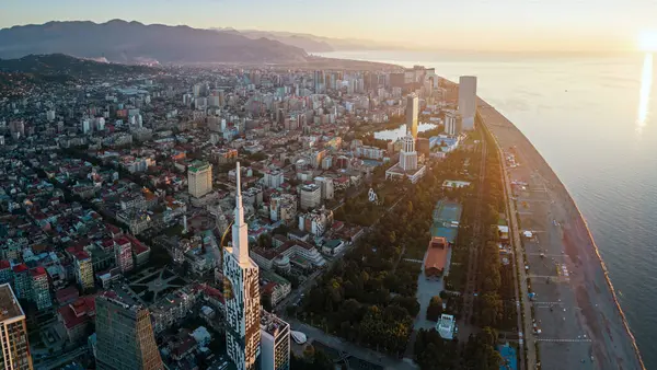 Günbatımında modern gökdelenleri, kıyı şeridi ve dağları olan Batumi, Gürcistan 'ın hava manzarası.