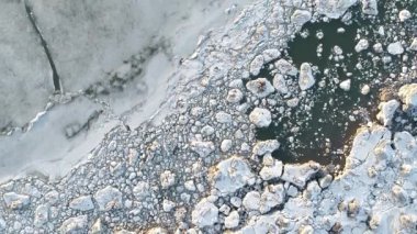 Parçalanmış buz kütlelerinin yukarıdan aşağı perspektifi karanlık sularda sürükleniyor..