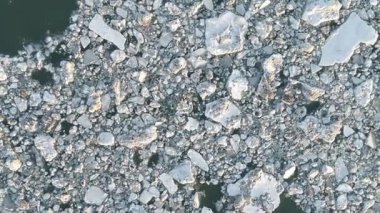 Parçalanmış buz kütlelerinin yukarıdan aşağı perspektifi karanlık sularda sürükleniyor..