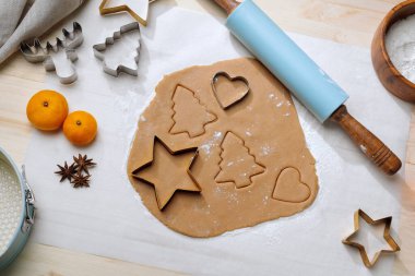 Kurabiye şekilli zencefilli kurabiye hamuru. Etrafı kesiciler ve malzemelerle çevrili..