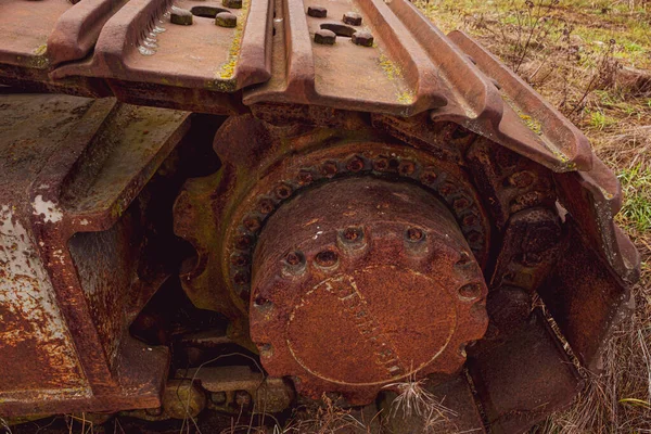 Rusty and dirt covered mechanical caterpillar track with aged cogs and wheels.