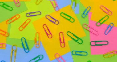 Multicolored paper clips on a rotating table with multicolored paper Sticky Notes, post it