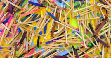 matchsticks of various shapes and colors on a rotating table with multicolored paper sticky notes on background