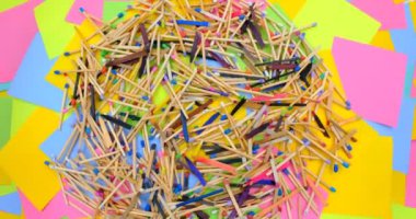 matchsticks of various shapes and colors on a rotating table with multicolored paper sticky notes on background