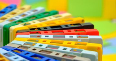 Çok renkli eski antika ses kasetlerinden oluşan bir koleksiyon. Çok renkli kağıt yapışkan notaların arka planına sahip dönen bir masa üzerinde.