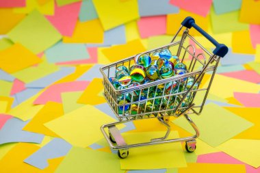 Dekoratif cam topları olan bir alışveriş arabası arka planda renkli kağıt yapışkan notlar.