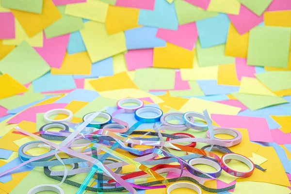 rolls of decorative adhesive tape on a background of multicolored paper sticky notes