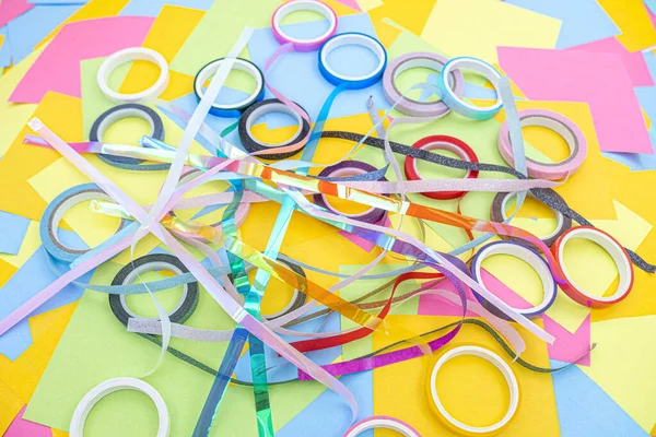 rolls of decorative adhesive tape on a background of multicolored paper sticky notes