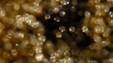 Altın parıltılı arka plan. Gerçek altın parçacıkları ile güzel bir geçiş. Siyah zemin üzerinde rüzgarda uçan, alanın derinliğiyle çekilen.