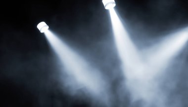 Projektörler sahnede dumandan ışık saçıyor.