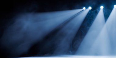 Projektörler sahnede dumandan ışık saçıyor.