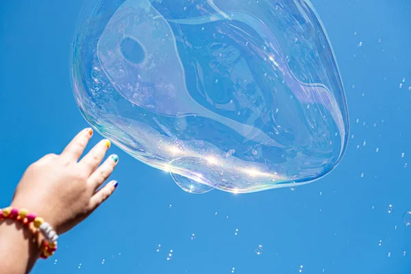 空に上昇するいくつかの石鹸泡をキャッチしようとしている子供の手 — ストック写真