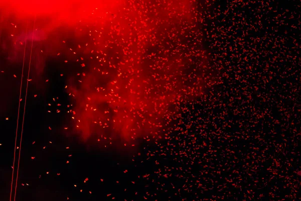 Shiny red confetti falling down on black background