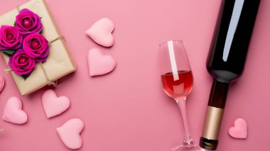 Sevgililer Günü hediyesinin en üst görüntüsü şarap ve pembe gül buketi ile pembe arka plan tasarımı konsepti.