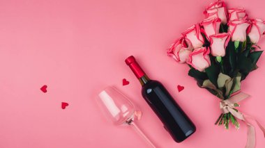 Sevgililer Günü hediyesinin en üst görüntüsü şarap ve pembe gül buketi ile pembe arka plan tasarımı konsepti.