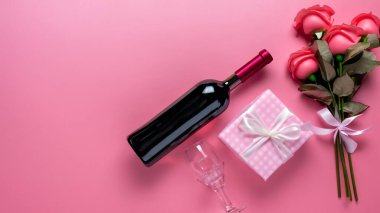 Sevgililer Günü hediyesinin en üst görüntüsü şarap ve pembe gül buketi ile pembe arka plan tasarımı konsepti.