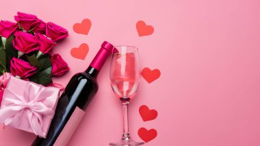 Sevgililer Günü hediyesinin en üst görüntüsü şarap ve pembe gül buketi ile pembe arka plan tasarımı konsepti.