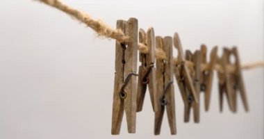 Eski ahşap mandallar, çamaşır askıları kenevir ipinde, beyaz arka planda.