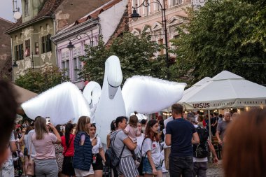 Sibiu City, Romania - 01 July 2022. The street parade with artists in swan costumes during the International Theatre Festival from Sibiu, Romania. clipart