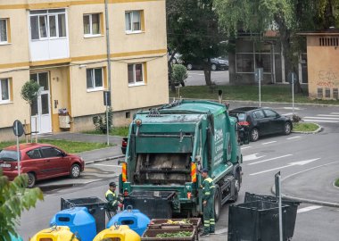 Sibiu City, Romanya - 29 Mayıs 2024. İşçiler konteynırı çöplerle dolduruyor, sokak temizliği, çöpleri boşaltan adamlar.