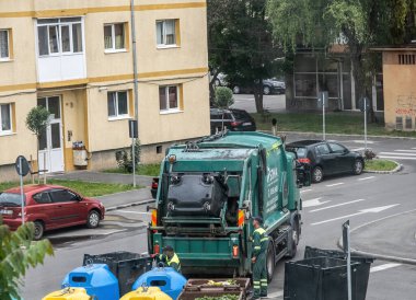 Sibiu City, Romanya - 29 Mayıs 2024. İşçiler konteynırı çöplerle dolduruyor, sokak temizliği, çöpleri boşaltan adamlar.