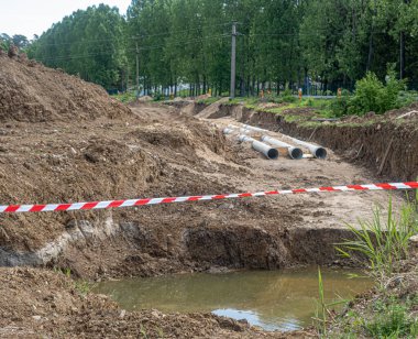 Siperdeki yeni fiber cam boru hattı. Eski paslı boruların yenisiyle değiştirilmesi. Rüzgarda sallanan kırmızı beyaz uyarı şeridiyle çevrili.