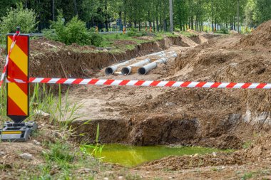 Siperdeki yeni fiber cam boru hattı. Eski paslı boruların yenisiyle değiştirilmesi. Rüzgarda sallanan kırmızı beyaz uyarı şeridiyle çevrili.