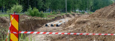 Siperdeki yeni fiber cam boru hattı. Eski paslı boruların yenisiyle değiştirilmesi. Rüzgarda sallanan kırmızı beyaz uyarı şeridiyle çevrili.