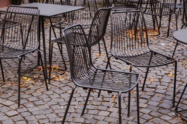 kaldırımda demir masalar ve sandalyeler ve sonbahar yaprakları