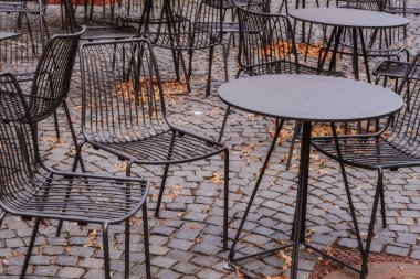 kaldırımda demir masalar ve sandalyeler ve sonbahar yaprakları