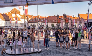 SIBIU, ROMANIA - 30 Haziran 2023 Romanya 'nın Sibiu kentinde düzenlenen Uluslararası Tiyatro Festivali sırasında büyük meydandaki dev aynaların yansımasında.