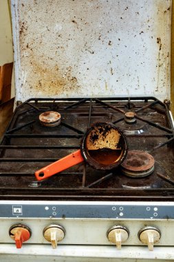 Kirli bir kahve demliği kirli bir sobaya dökülmüş.