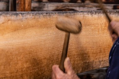 A man using two wooden mallets to beat a wooden semantron. A man using two wooden mallets to beat a wooden semantron clipart