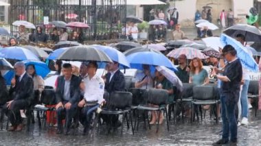 Sibiu City, Romanya - 11 Haziran 2024. Şiddetli bir yağmurun altında öğrencilerin şapkalarını havaya attıkları mezuniyet töreni.