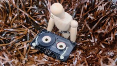 Geçmiş konsepti, sargılanmamış manyetik bantlarla çevrili ahşap bir manken elinde eski bir ses kaseti tutar. 