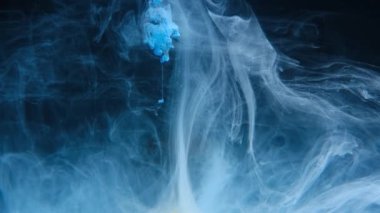 Blue ink drops in water on black background