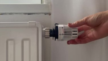 Hand of woman adjusting heating radiator valve