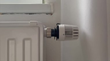 Hand of woman adjusting heater temperature knob at home