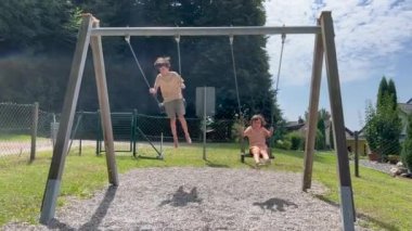 Brother and sister having fun on swing at park