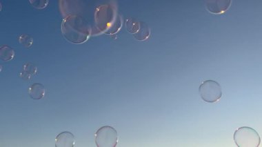 Soap bubbles flying outdoors against blue sky