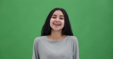 Yeşil renkli arka planda gülen güzel bir genç kadının portresi.